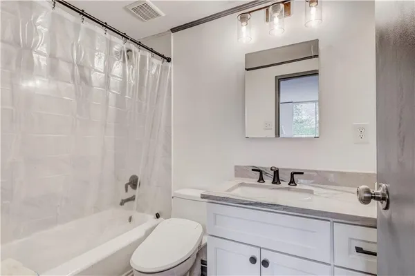 a bathroom with a toilet a sink a mirror a bathtub and vanity