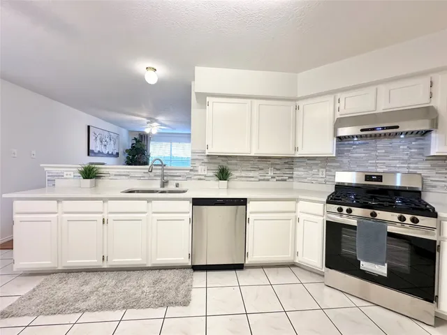 a kitchen with a sink chairs and white cabinets