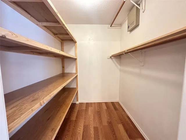 an empty room with wooden floor chandelier fan and windows