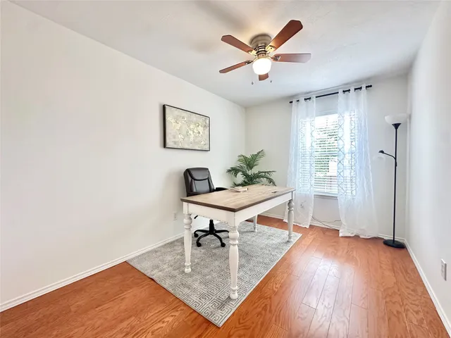 an empty room with wooden floor ceiling fan and windows