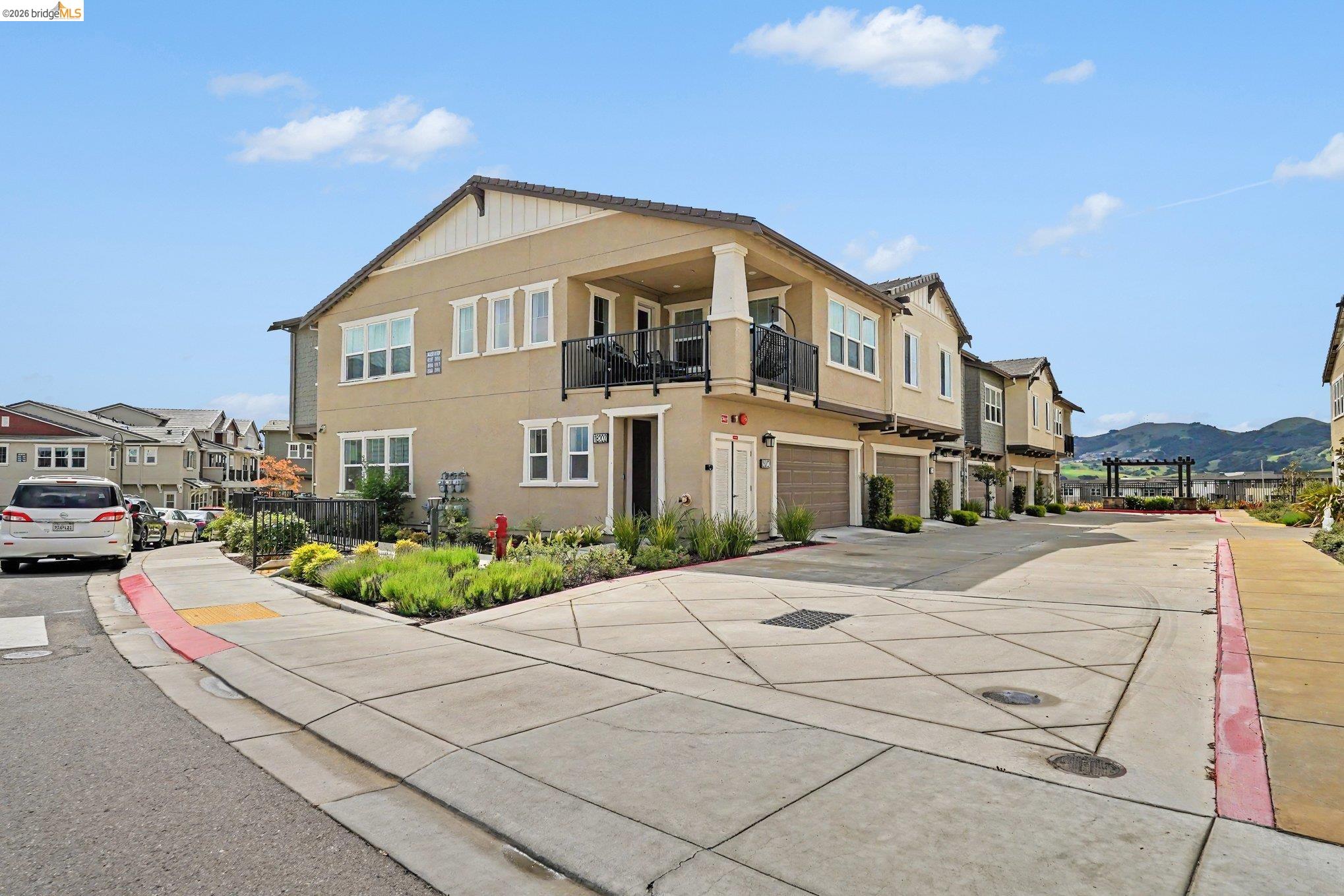 18210 Argento Loop San Ramon, CA 94583 - Photo 38 of 44 Contemporary multi-story residence featuring a stucco exterior, integrated garage, upper-level balcony with black iron railing, and a landscaped entry with mature plantings