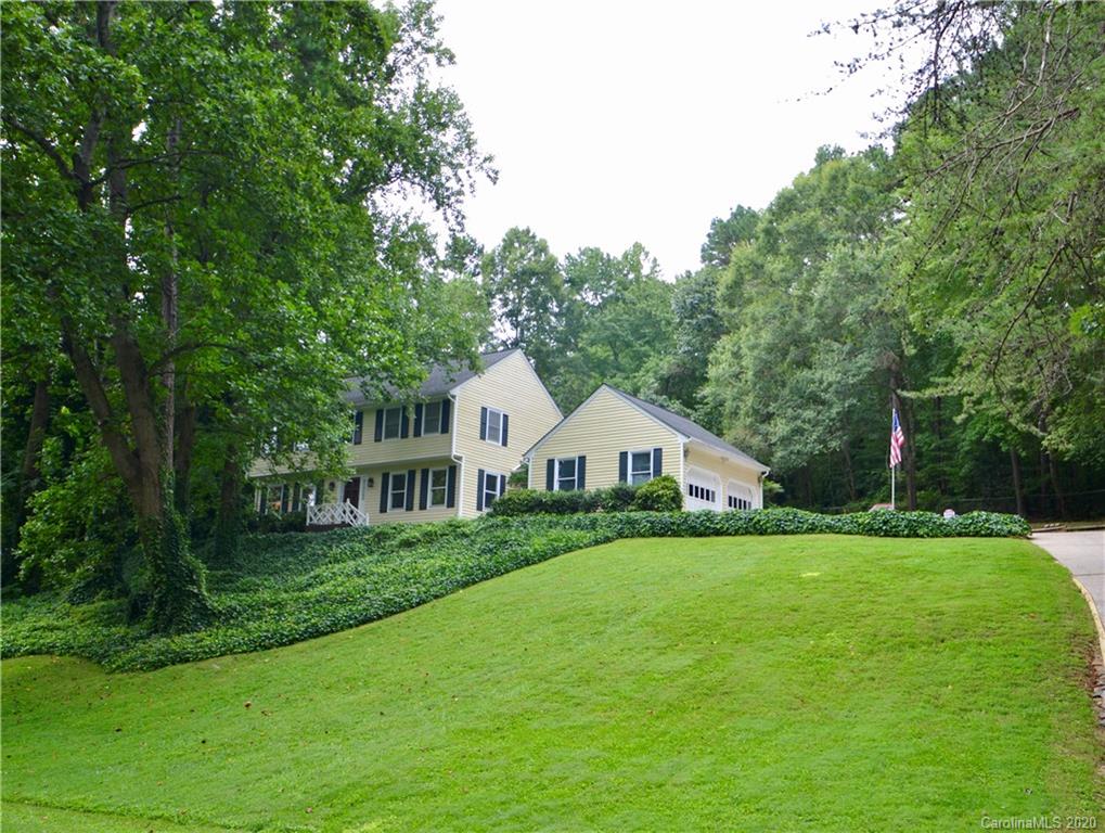 a view of a house with a big yard potted plants and large tree