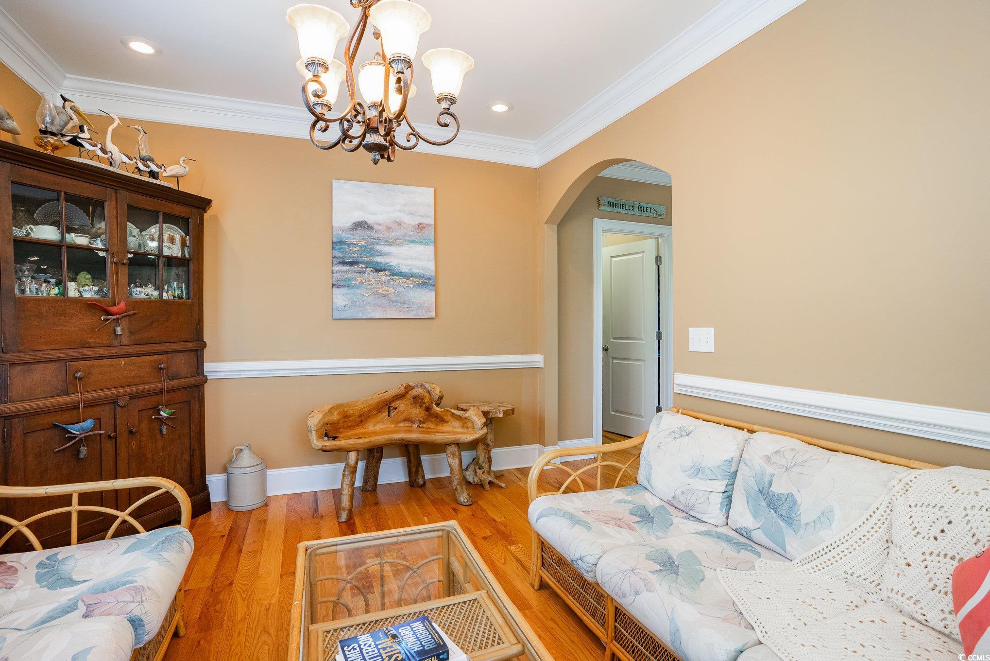 9 Gasparilla Drive Murrells Inlet, SC 29576 - Photo 8 of 40 Living area with baseboards, a chandelier, crown molding, arched walkways, and wood finished floors