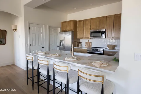 a kitchen with stainless steel appliances granite countertop a table chairs microwave and sink