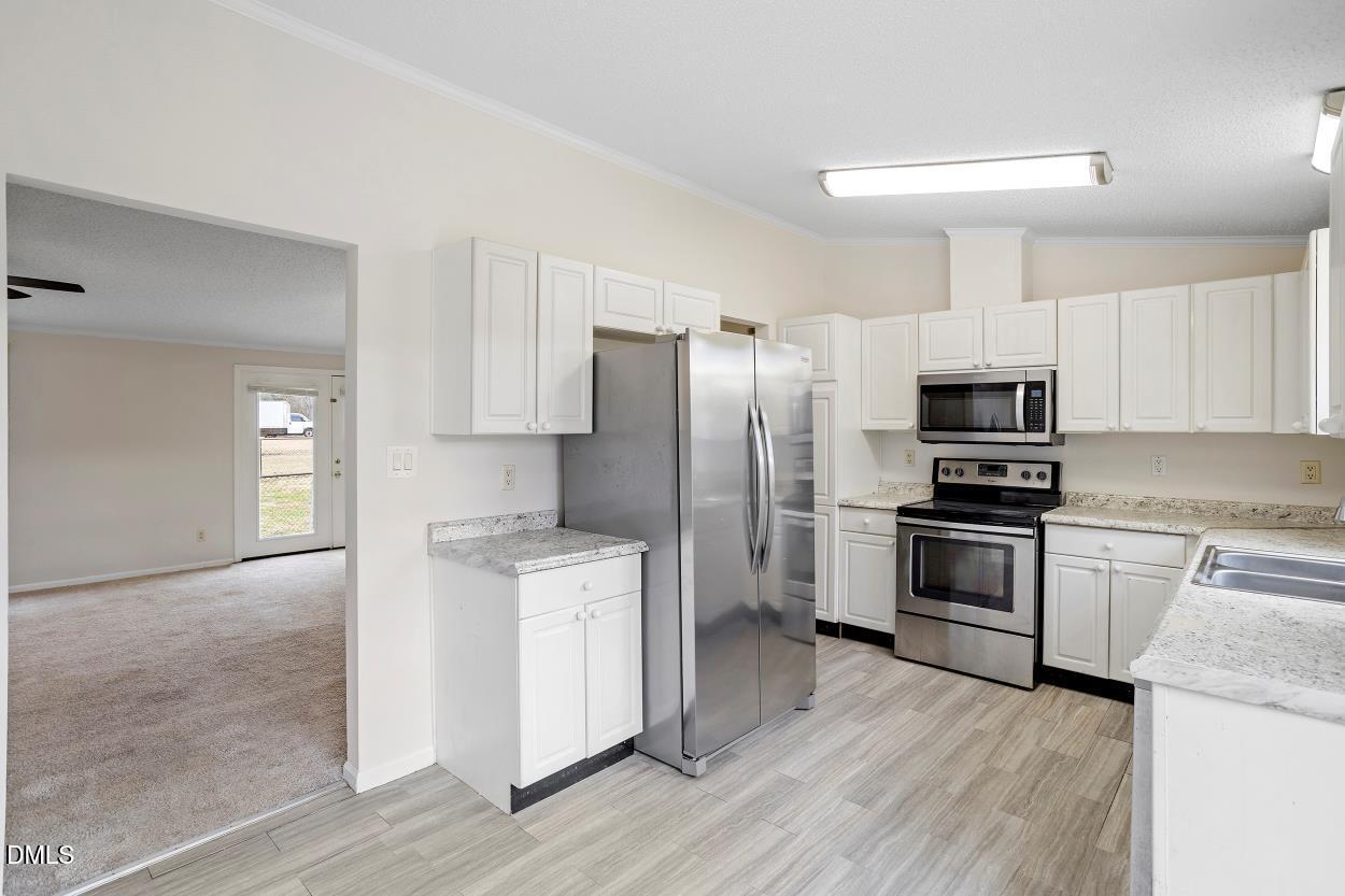 919 Red Mountain Road Rougemont, NC 27572 - Photo 15 of 32 a kitchen with a refrigerator stove and wooden cabinets
