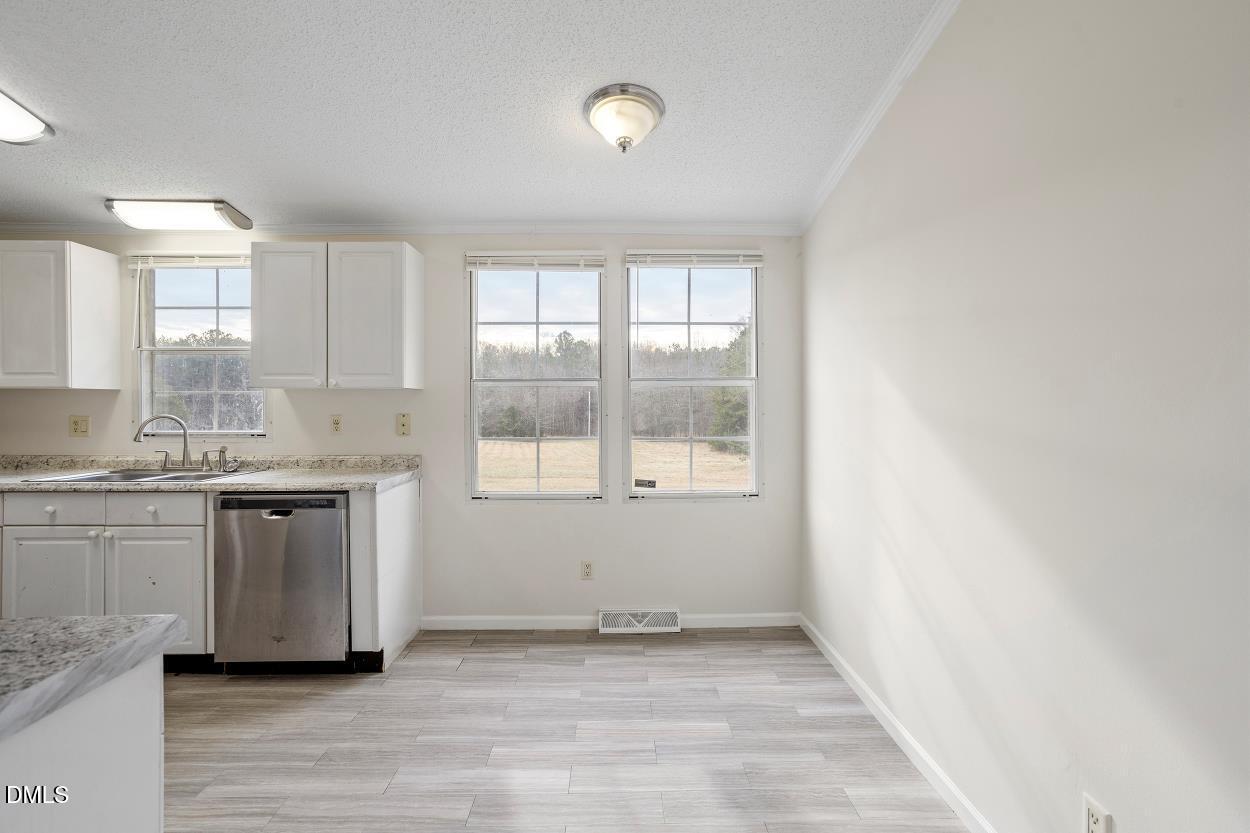 919 Red Mountain Road Rougemont, NC 27572 - Photo 16 of 32 a kitchen with granite countertop white cabinets and a wooden floor