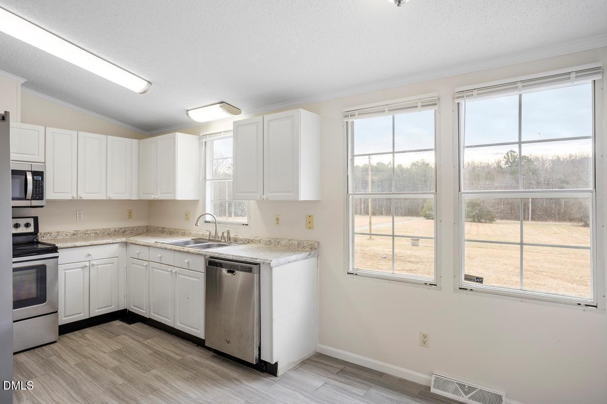 919 Red Mountain Road Rougemont, NC 27572 - Photo 17 of 32 a kitchen with a sink cabinets wooden floor and a window