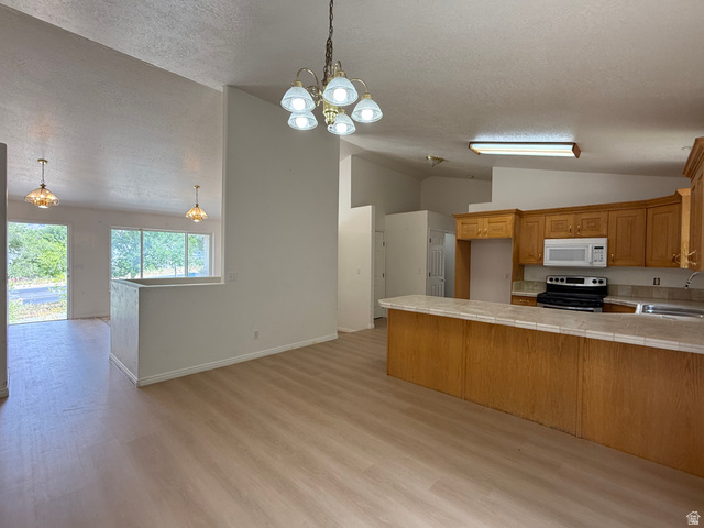 838 East Mountain Road Logan, UT 84321 - Photo 6 of 37 Open-concept kitchen and living area featuring wood-finish flooring, vaulted ceilings, and a kitchen island with a tiled countertop