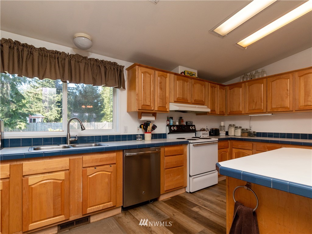 5004 186th Lane Southwest Rochester, WA 98579 - Photo 10 of 27 a kitchen with granite countertop wooden cabinets a sink a window and stainless steel appliances