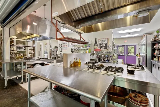 a room with stainless steel appliances lots of white furniture a dining table and chairs