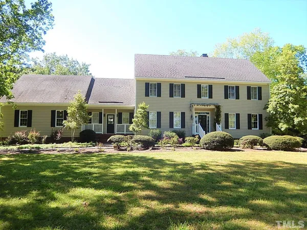 a front view of house with yard and trees in the background