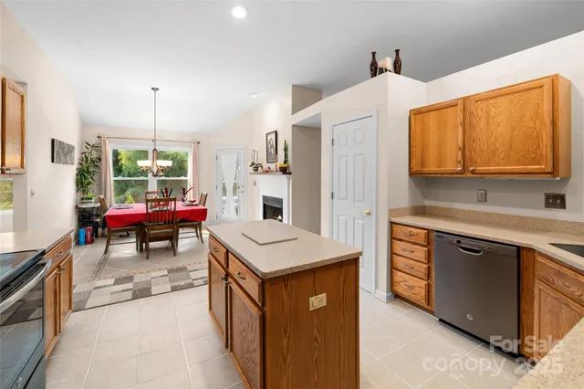 a kitchen with stainless steel appliances kitchen island granite countertop a refrigerator a stove a sink dishwasher and a dining table with the living room view