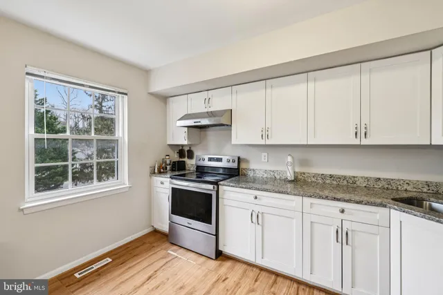 a kitchen with granite countertop white cabinets and appliances