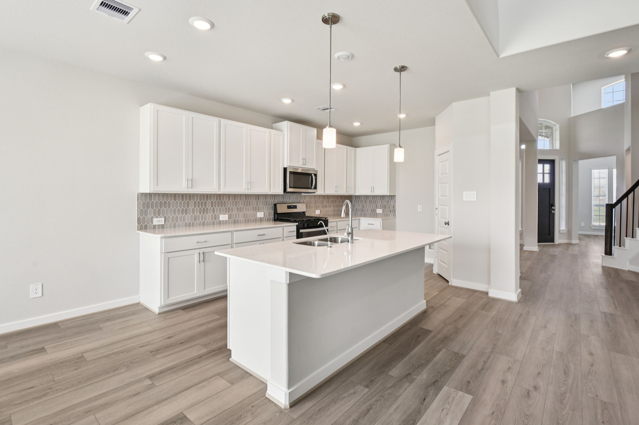 2843 Dark Lantern Drive Rosenberg, TX 77471 - Photo 3 of 49 a kitchen with kitchen island a sink a stove a refrigerator and white cabinets with wooden floor