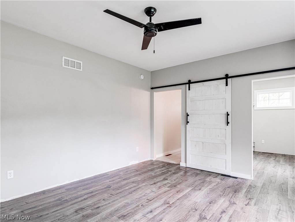 6573 Boneta Road Medina, OH 44256 - Photo 31 of 38 Bedroom with a barn door, light wood-type flooring, and ceiling fan
