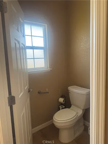 a white toilet sitting next to a window in a bathroom