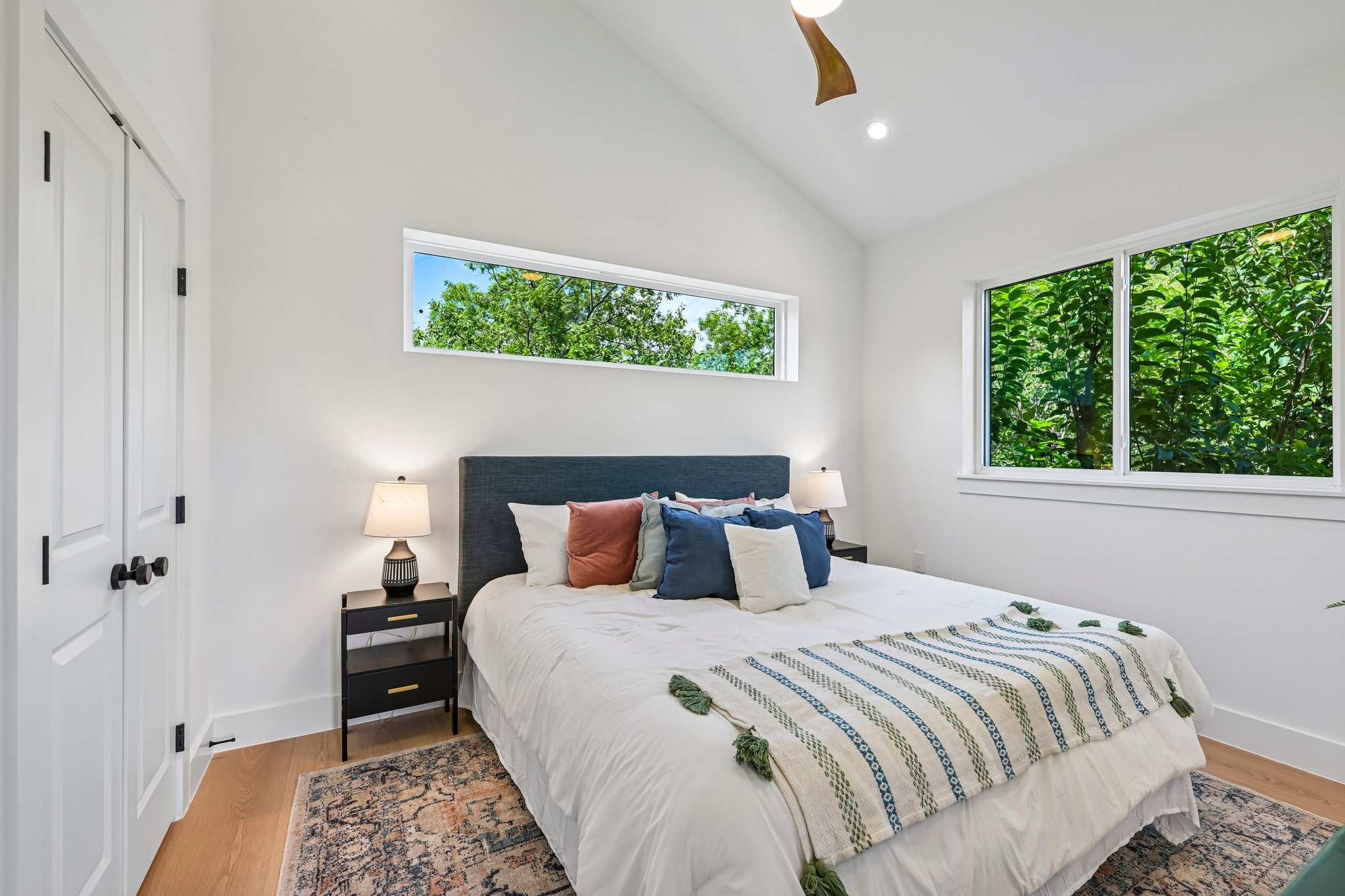 513 West Odell Street, Unit B Austin, TX 78752 - Photo 15 of 38 A tranquil primary bedroom with vaulted ceilings and verdant outdoor views among the trees.