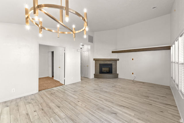 301 South 1200th Street East, Unit 31 St. George, UT 84790 - Photo 10 of 21 Unfurnished living room with light wood finished floors, suspended lighting, and a fireplace with raised hearth
