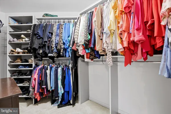 a view of walk in closet with clothes and shoes