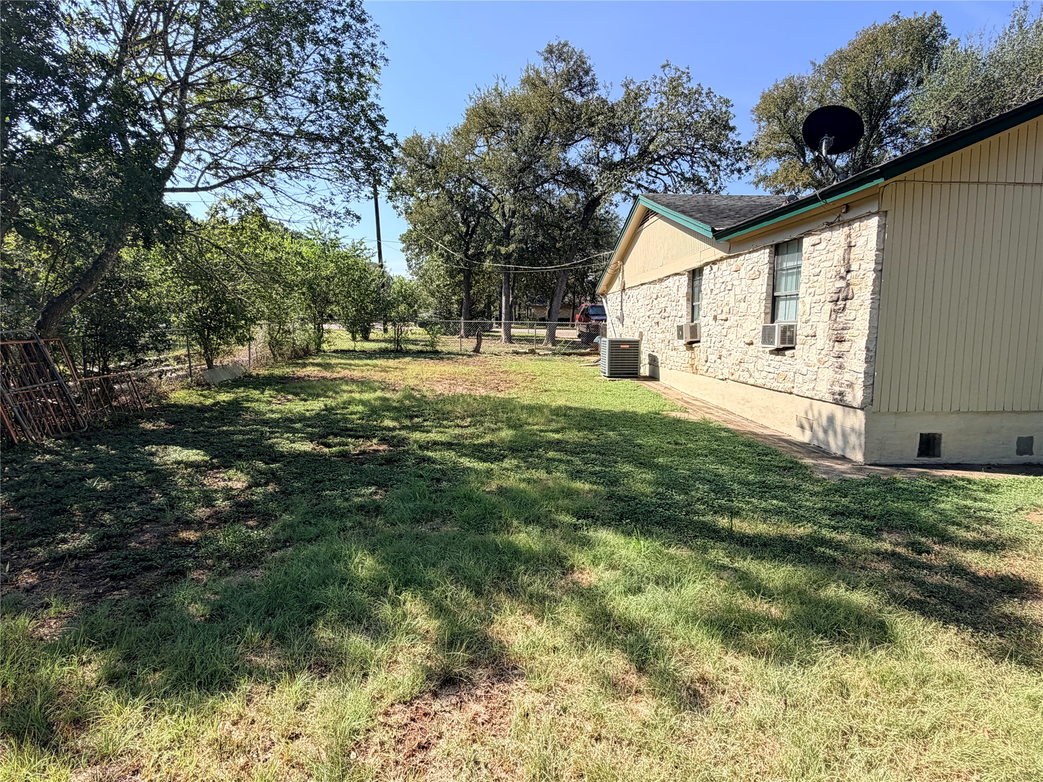 2800 Robin Road Manchaca, TX 78652 - Photo 27 of 28 A spacious grassy lawn borders the side of this home under a clear blue sky.