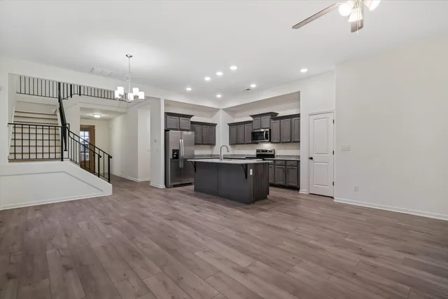 a large kitchen with stainless steel appliances a large counter top a chandelier and a refrigerator