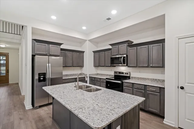 a kitchen with stainless steel appliances granite countertop a kitchen island hardwood floor sink and stove