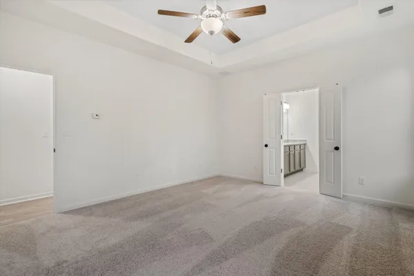 a view of an empty room and chandelier fan
