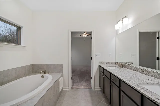 a bathroom with a granite countertop tub sink and mirror