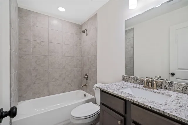 a bathroom with a granite countertop sink a toilet and bathtub