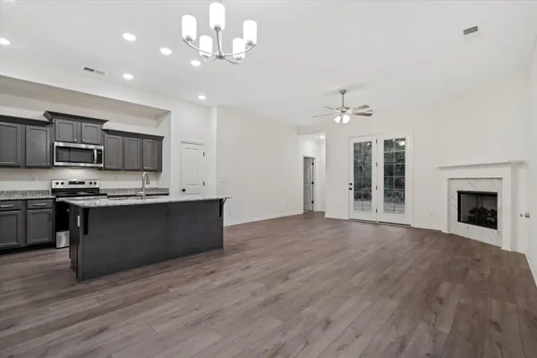 a large kitchen with kitchen island granite countertop a stove top oven a sink with dishwasher and white cabinets