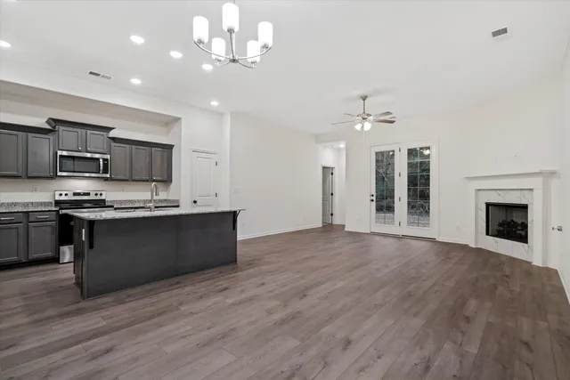 a large kitchen with kitchen island granite countertop a stove top oven a sink with dishwasher and white cabinets