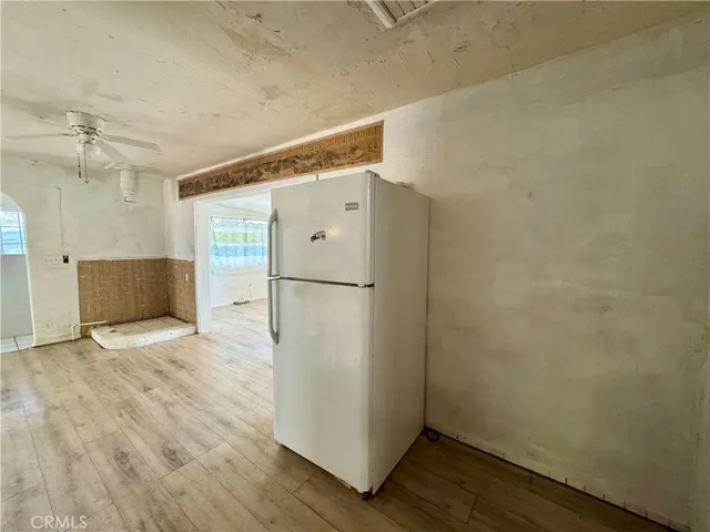 a view of a refrigerator in kitchen and an empty room