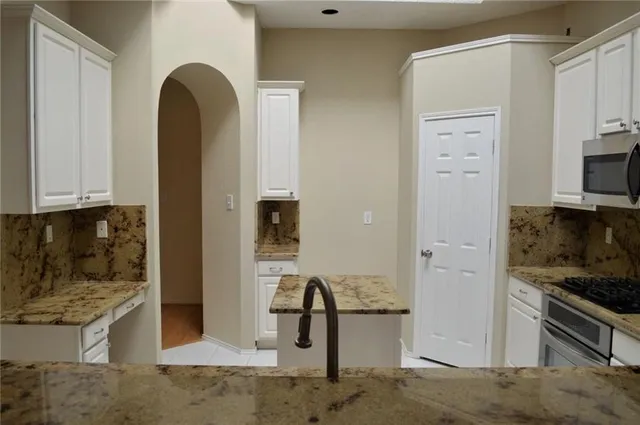 a view of kitchen with stainless steel appliances granite countertop cabinets and window