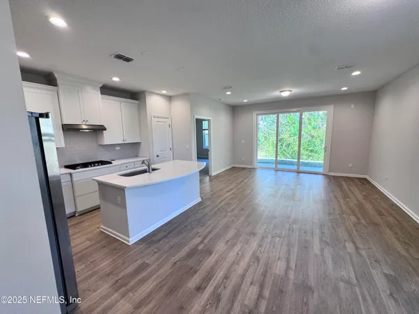a kitchen with stainless steel appliances kitchen island wooden floors wooden cabinets and entryway