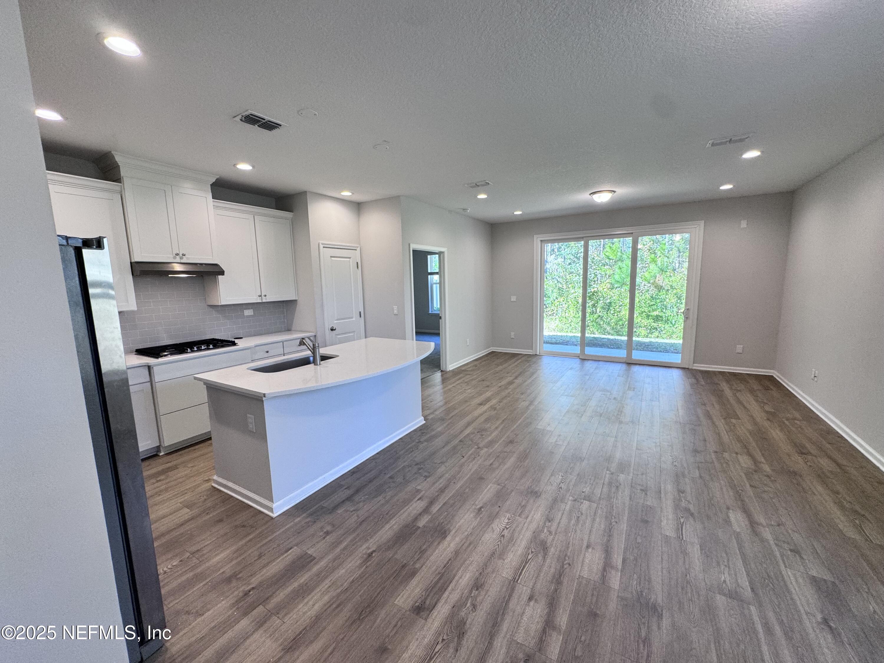 156 Charlie Way St. Augustine, FL 32095 - Photo 4 of 33 a kitchen with stainless steel appliances kitchen island wooden floors wooden cabinets and entryway