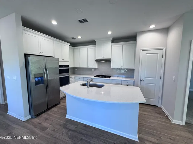 a kitchen with kitchen island a counter top space a refrigerator a sink and cabinets