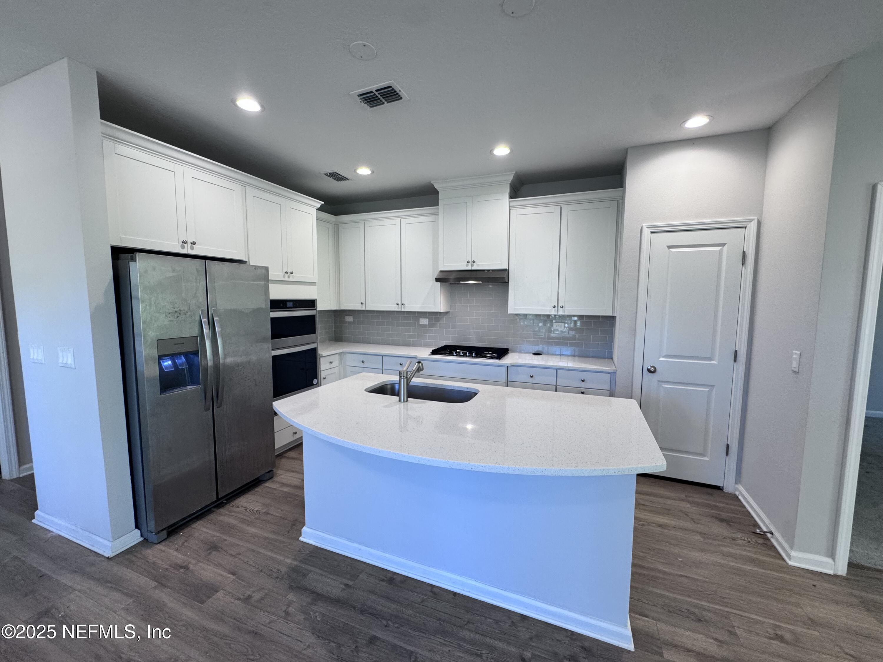 156 Charlie Way St. Augustine, FL 32095 - Photo 5 of 33 a kitchen with kitchen island a counter top space a refrigerator a sink and cabinets