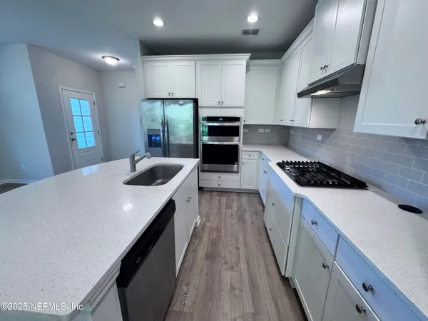 a kitchen with kitchen island white cabinets appliances and window