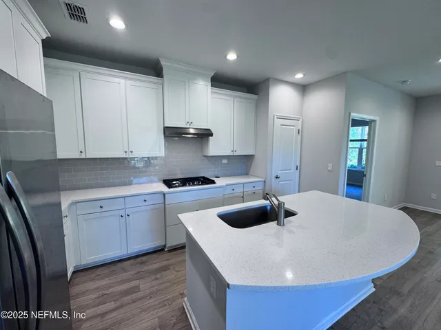 a kitchen with stainless steel appliances a white stove top oven a sink a refrigerator and white cabinets