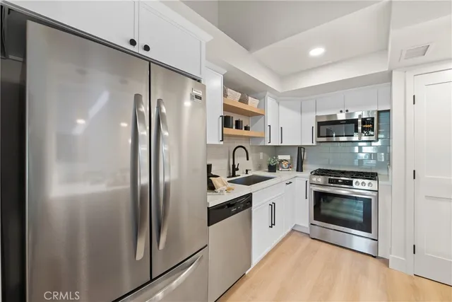 a kitchen with stainless steel appliances granite countertop a refrigerator a stove and a sink