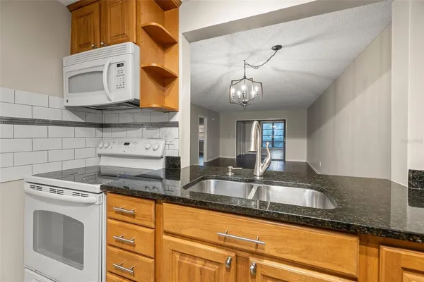 a kitchen with granite countertop a sink a stove and cabinets