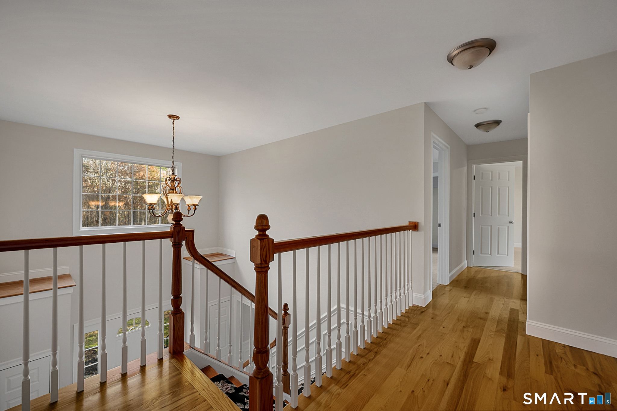 a view of a hallway with wooden floor and chandelier