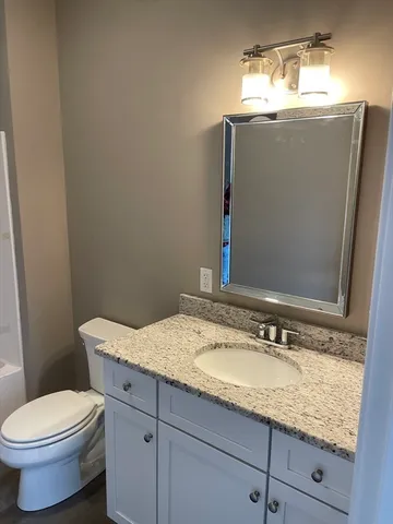 a bathroom with a granite countertop toilet sink and mirror