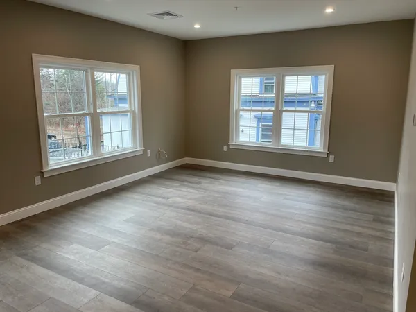 an empty room with wooden floor and windows