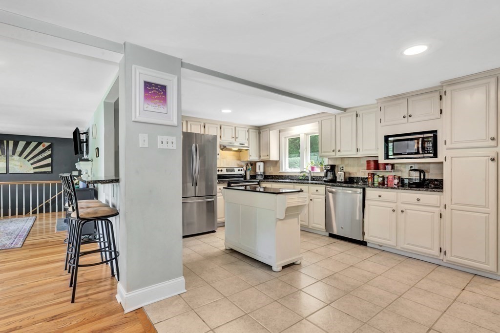 49 Woodland Road Ashland, MA 01721 - Photo 7 of 36 a kitchen with white cabinets a sink a window and stainless steel appliances