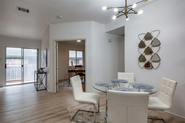 a dining room with wooden floor a chandelier a wooden table and chairs
