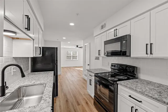 a kitchen with stainless steel appliances granite countertop a stove top oven a sink dishwasher a refrigerator with wooden cabinets and floor