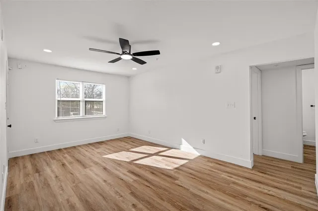 a view of empty room with wooden floor and fan