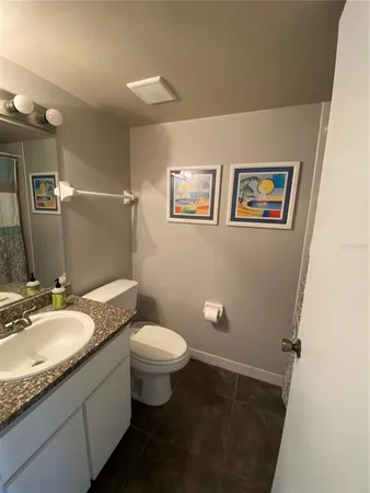 a bathroom with a granite countertop sink mirror vanity and toilet