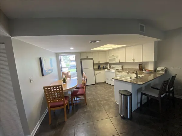 a kitchen with a dining table chairs and white cabinets